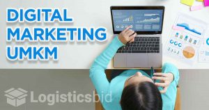 Seorang wanita memegang stylus dan bekerja di laptop yang menampilkan grafik pemasaran digital dengan teks 'DIGITAL MARKETING UMKM' dan logo di sudut kanan bawah.